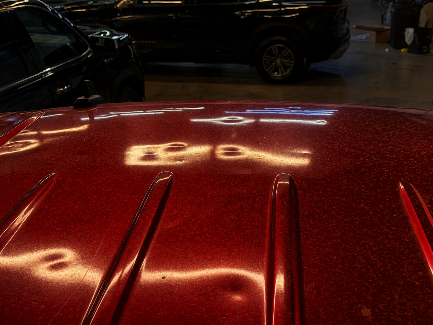 Red pickup — hood dent mapping under reflective lighting.